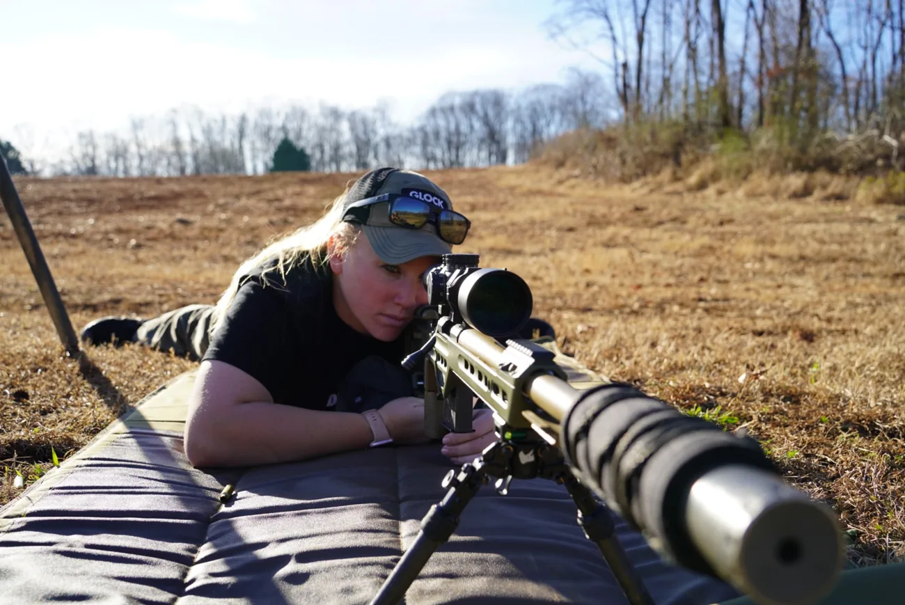 A shooter in the prone position behind a scoped precision rifle